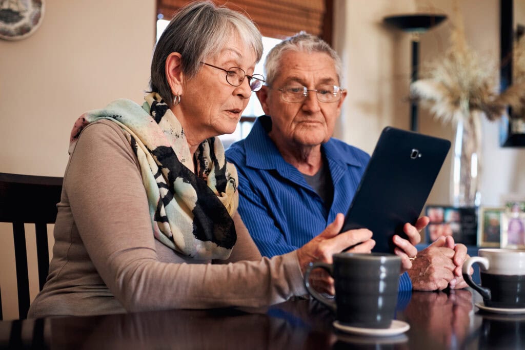 senior couple at home making video call to family or watching movie on digital tablet