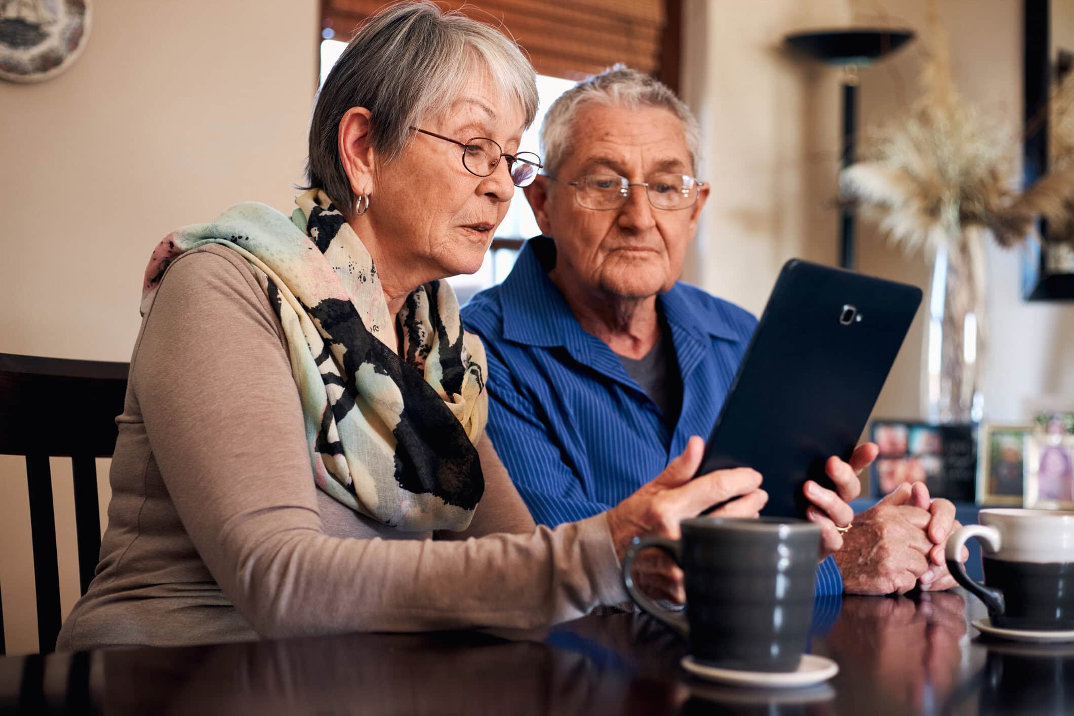 senior couple at home making video call to family or watching movie on digital tablet